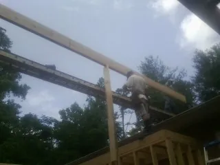 Carpenter setting a ridge beam over a new addition frame — Ice Dam Removal by Roofing Brothers in Port Saint Joe
