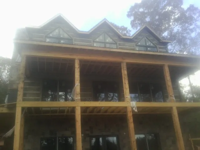 Dormers and porch framing on a large log home under construction — Roof Coating work by our crew in Port Saint Joe