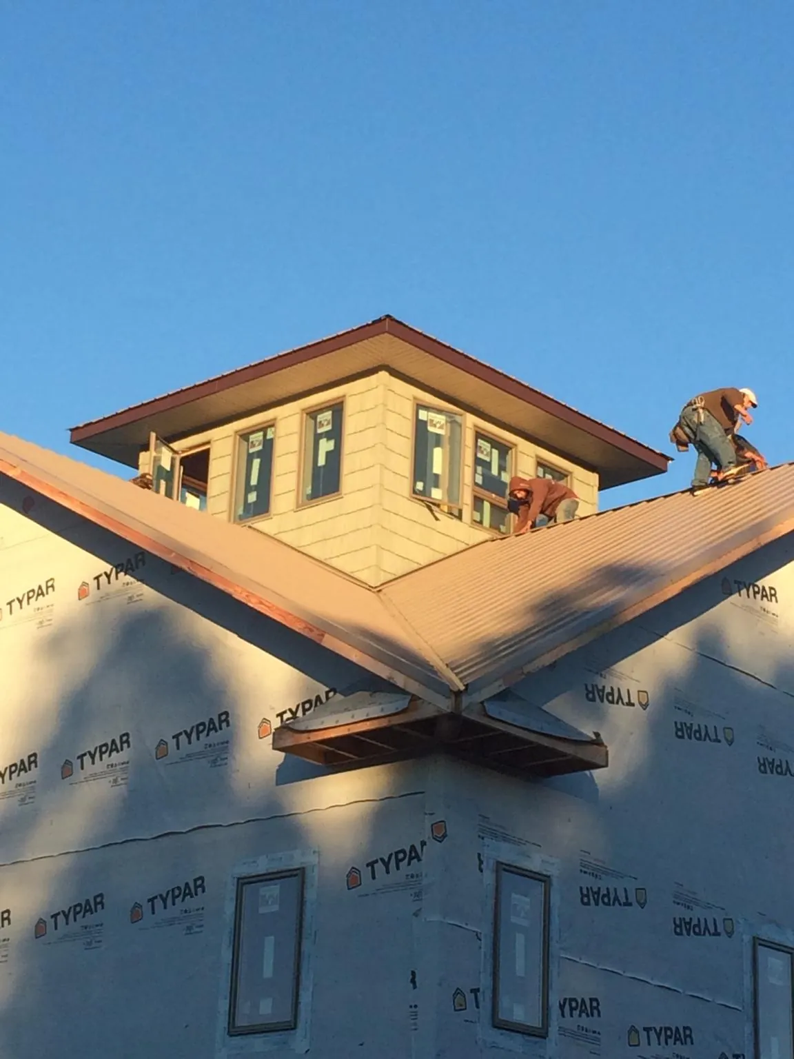 Roofers working around a rooftop cupola on a new metal roof at sunset — Roof Waterproofing in Port Saint Joe by Roofing Brothers